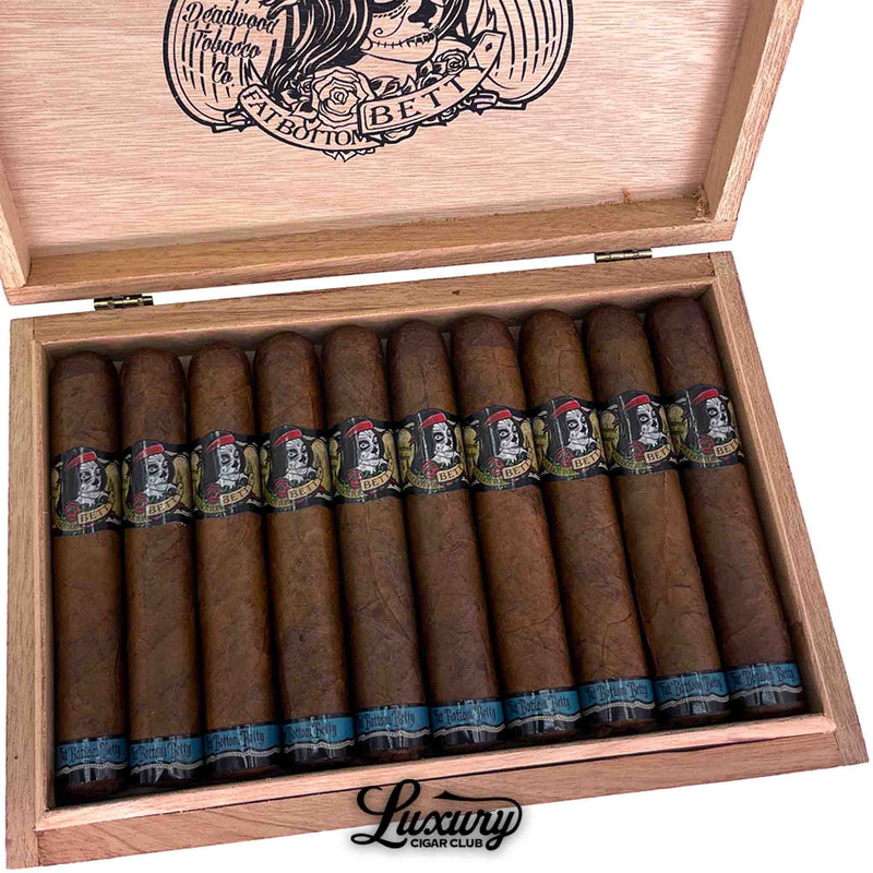 Close up shot of Deadwood Tobacco Co. Fat Bottom Betty Robusto cigars inside open wooden box, featuring detailed sugar skull cigar bands and visible wrapper texture.