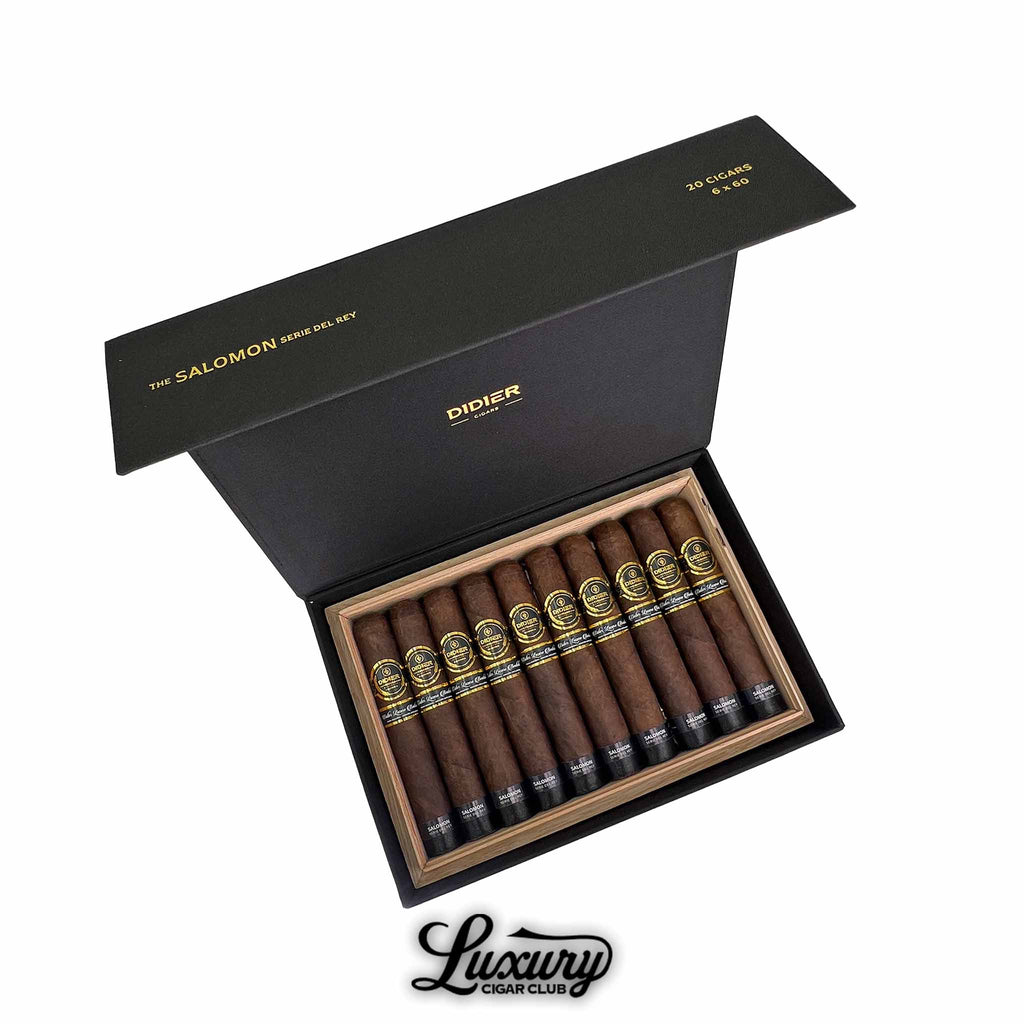 Open box of Didier Salomon Serie Del Rey cigars with dark brown wrappers, gold and black bands, neatly arranged in a wooden box inside black packaging.