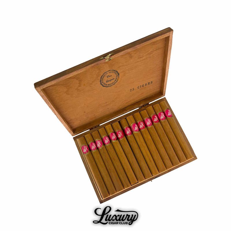 Open box of Don Quijote No. 5 cigars with light brown wrappers and pink bands, arranged in two rows inside wooden box, Luxury Cigar Club logo
