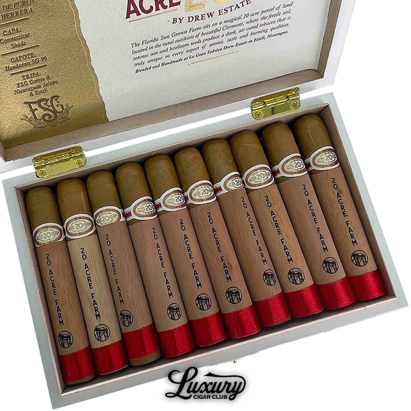 Close-up of Drew Estate 20 Acre Farm Robusto cigars arranged in a white box. Each cigar is wrapped in cedar with red foil at the foot and gold bands. Luxury Cigar Club logo underneath.
