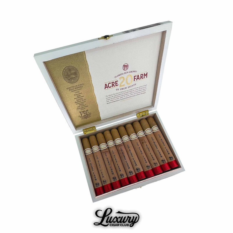 Open box of Drew Estate 20 Acre Farm Toro cigars showing light Connecticut wrappers and cedar-wrapped bodies with red foot bands and gold accents. Luxury Cigar Club logo visible below.