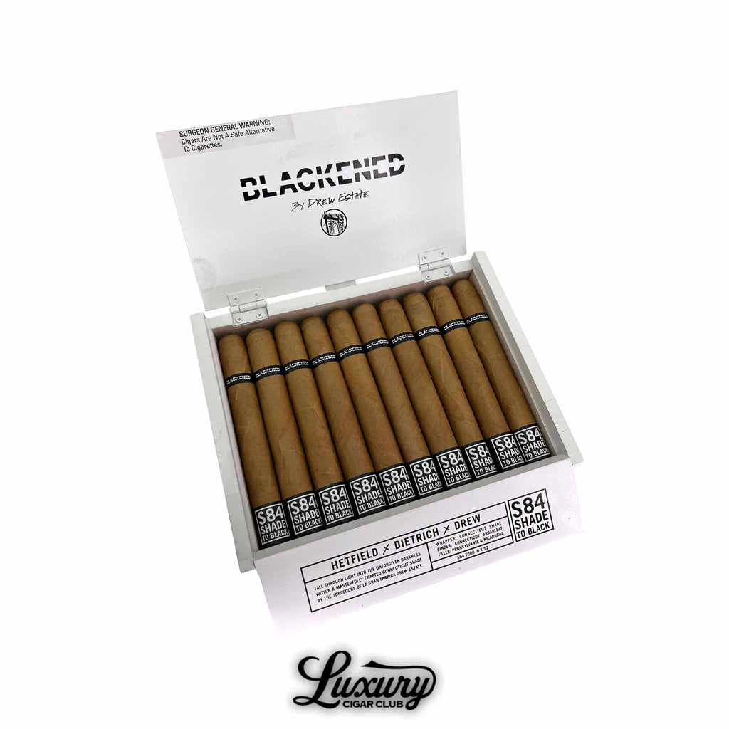 Open white box of Drew Estate Blackened S84 Shade to Black Toro cigars with bold black-and-white branding. Cigars feature smooth Connecticut shade wrappers and bands labeled “S84 Shade to Black.” Luxury Cigar Club logo below.
