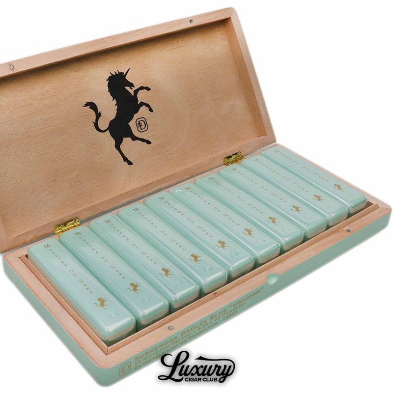 Close-up of Dunbarton Tobacco & Trust Brûlée Blue Unicorn Diademas Deluxe box showcasing glossy mint-green packaging and refined gold unicorn detailing, presented by Luxury Cigar Club.