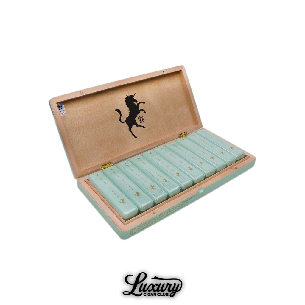 Dunbarton Tobacco & Trust Brûlée Blue Unicorn Diademas Deluxe cigars presented in an elegant mint-green box with gold accents and a black unicorn logo, available at Luxury Cigar Club.
