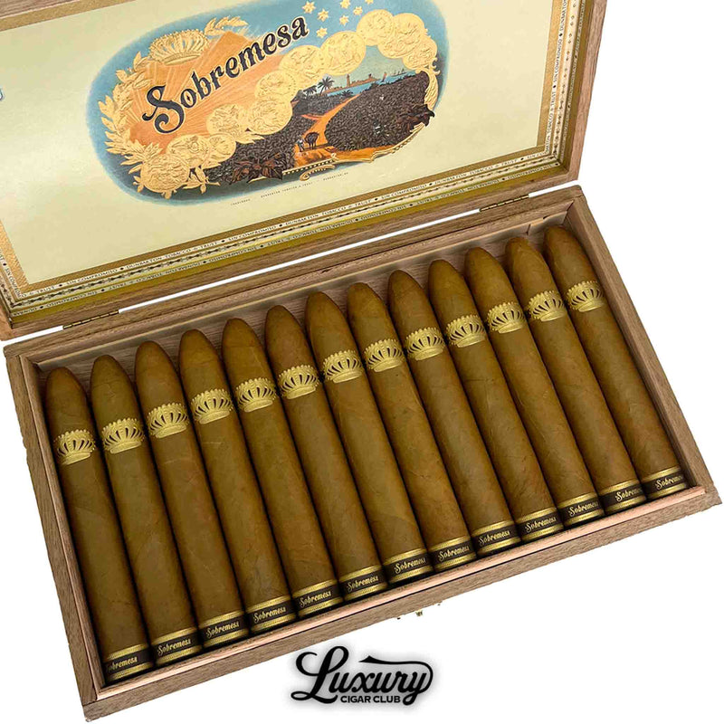 Close-up of Dunbarton Tobacco & Trust Sobremesa Brûlée Gordo cigars neatly arranged in a wooden box with golden Connecticut wrappers and embossed gold crown bands. Luxury Cigar Club logo beneath.
