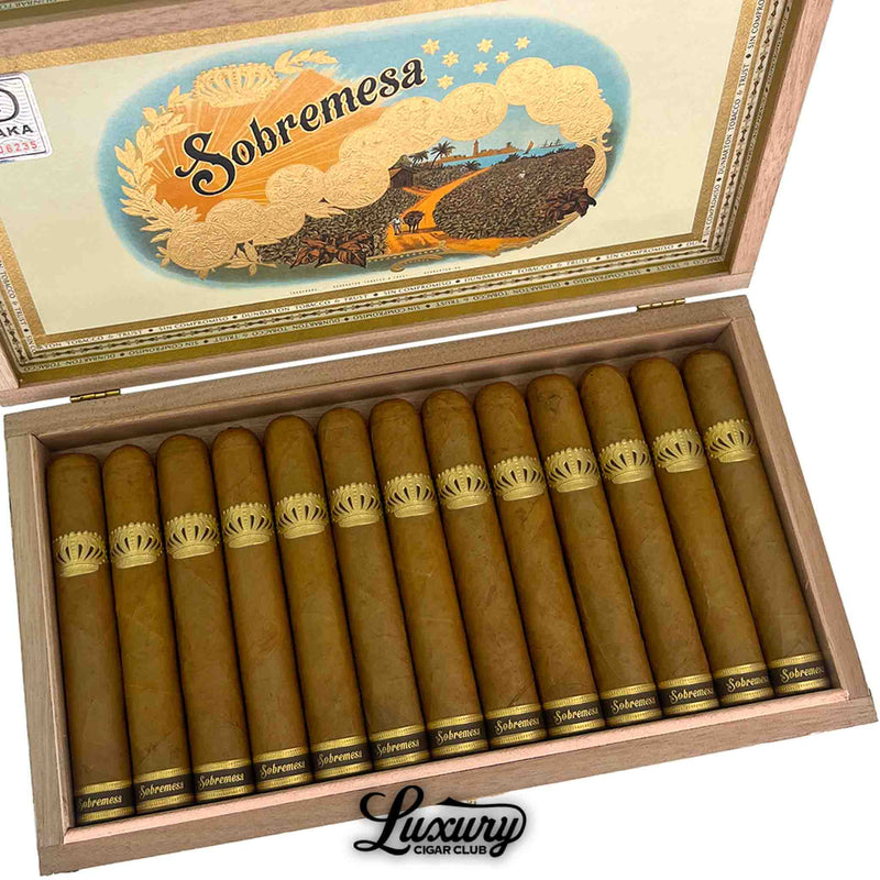 Close-up of Dunbarton Tobacco & Trust Sobremesa Brûlée Robusto cigars neatly arranged in an open wooden box, showcasing smooth Connecticut Shade wrappers with gold crown bands. Decorative Sobremesa artwork visible on the inside lid. Luxury Cigar Club logo below.