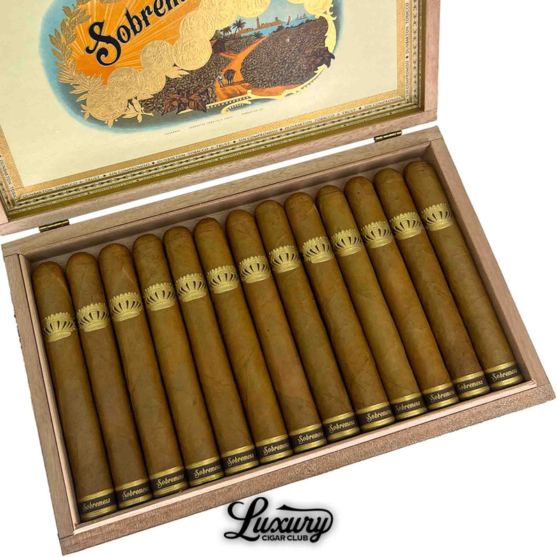 Close-up of Dunbarton Tobacco & Trust Sobremesa Brûlée Toro cigars in a wooden box, featuring smooth golden Connecticut wrappers and classic gold crown bands. Luxury Cigar Club logo beneath.