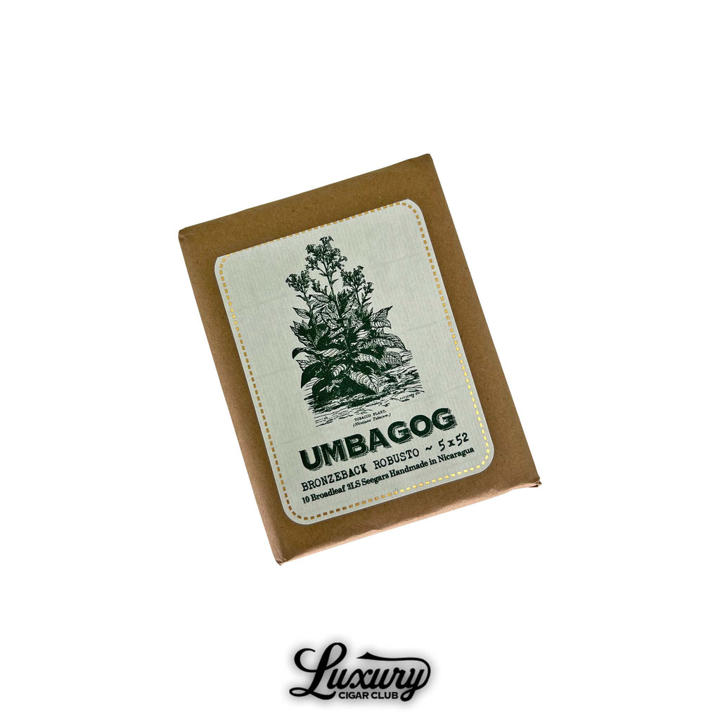 Dunbarton Tobacco & Trust Umbagog Bronzeback Robusto Cigars Pack. Brown paper-wrapped pack of 10 cigars featuring a white label with green plant illustration and gold accents, labeled “Umbagog Bronzeback Robusto 5x52,” from Luxury Cigar Club.