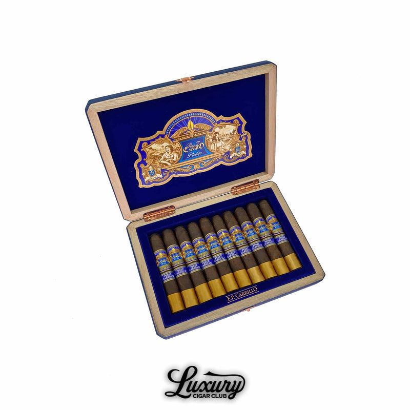 Open blue velvet lined box of EP Carrillo Pledge cigars with gold bands and ornate blue labels displayed in a row, shown for Luxury Cigar Club.
