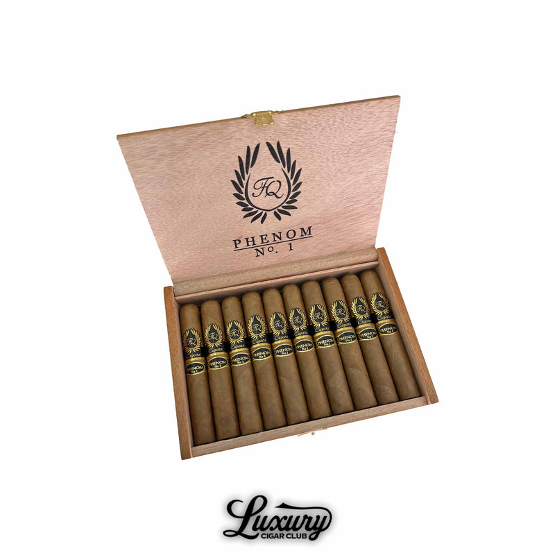 Open box of FQ Phenom No. 1 Robusto cigars with light brown wrappers and sleek black-and-gold bands. The inside lid features the FQ Cigars logo and “Phenom No. 1” text. Luxury Cigar Club logo below.