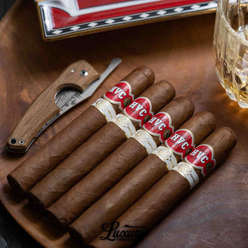 Fine Tobacco Club Ledger Series Vol. 1 HVC Robusto Extra cigars displayed on a wooden tray beside a cutter and glass, showcasing a premium lifestyle presentation by Luxury Cigar Club.