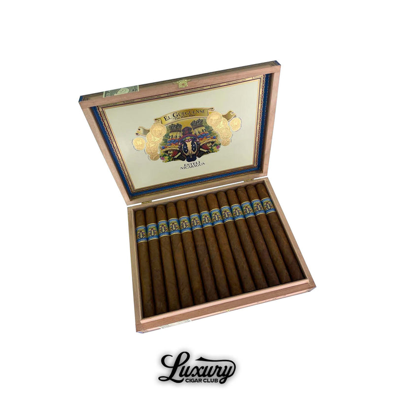 Open box of Foundation Cigars El Güegüense The Wise Man Churchill from Luxury Cigar Club, displaying long, premium cigars with blue-and-gold bands in a wooden box lined with gold trim and vibrant artwork.