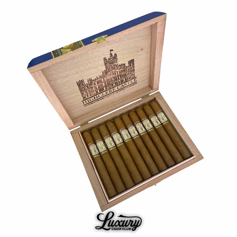 Open box of Foundation Highclere Castle Edwardian Corona cigars, displaying 10 light brown cigars with elegant cream and gold bands. The wooden lid features a detailed illustration of Highclere Castle and branded text, with “Luxury Cigar Club” logo below the box.