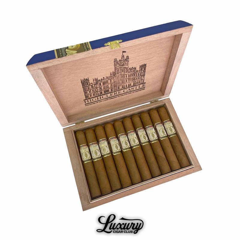 Open box of Foundation Highclere Castle Edwardian Robusto cigars, displaying 10 light brown cigars with elegant cream, gold, and red bands. The wooden lid features a detailed illustration of Highclere Castle and branded text, with “Luxury Cigar Club” logo beneath the box.