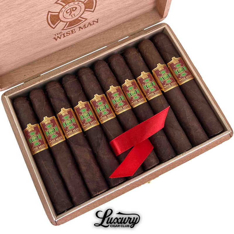 Close-up of Foundation The Wise Man Maduro Corona cigars arranged neatly in a wooden box from Luxury Cigar Club. The cigars showcase a dark, rich wrapper and feature bold red and gold bands with green detailing. A red ribbon rests across the cigars for elegant presentation, with the "Wise Man" logo engraved inside the box lid.