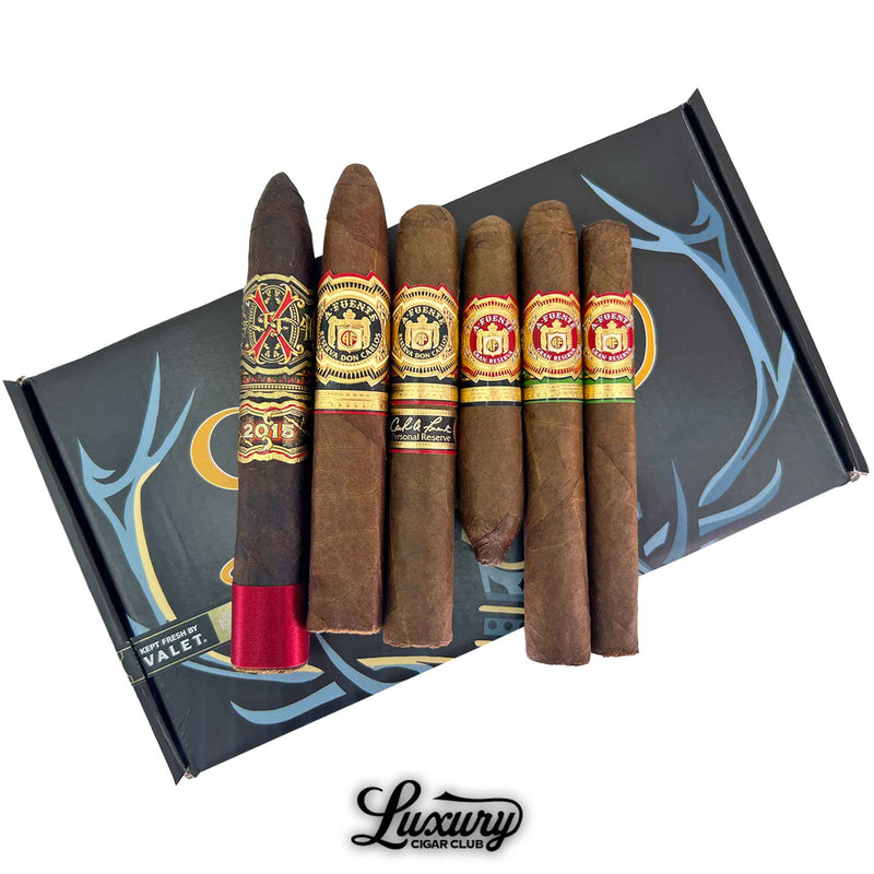 Close-up view of the Fuente Family Royal Collection Sampler showing six distinguished Arturo Fuente cigars with intricate bands and rich wrappers, arranged neatly on a branded presentation box by Luxury Cigar Club.