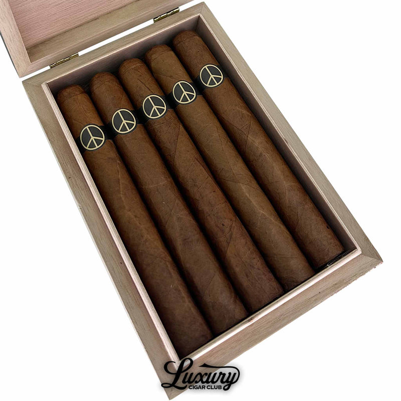 Open box of Illusione OneOff Black and Tan Toro Limited Edition cigars showing five medium-brown sticks with black and gold peace sign bands, presented by Luxury Cigar Club.