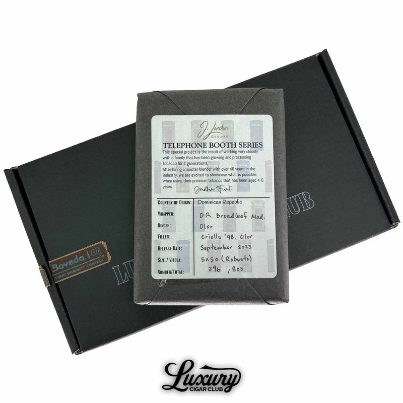 Back side of J London Telephone Booth Series Lavender Robusto gray wrapped bundle showing handwritten blend info and Tobacco origin details sitting on Luxury Cigar Club black shipping box