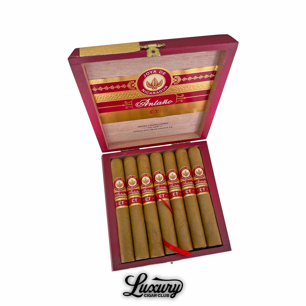 Joya de Nicaragua Antaño Connecticut Toro cigars displayed in an open red and gold box with elegant branding, showing golden-brown wrappers and red CT bands, presented by Luxury Cigar Club.