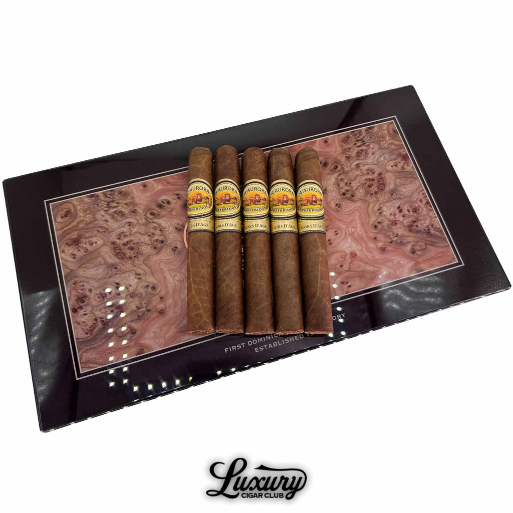 La Aurora Hors D’Age Limited Edition Toro cigars presented on a luxury wood-inlay box top, showcasing their elegant bands and expert craftsmanship, available at Luxury Cigar Club.