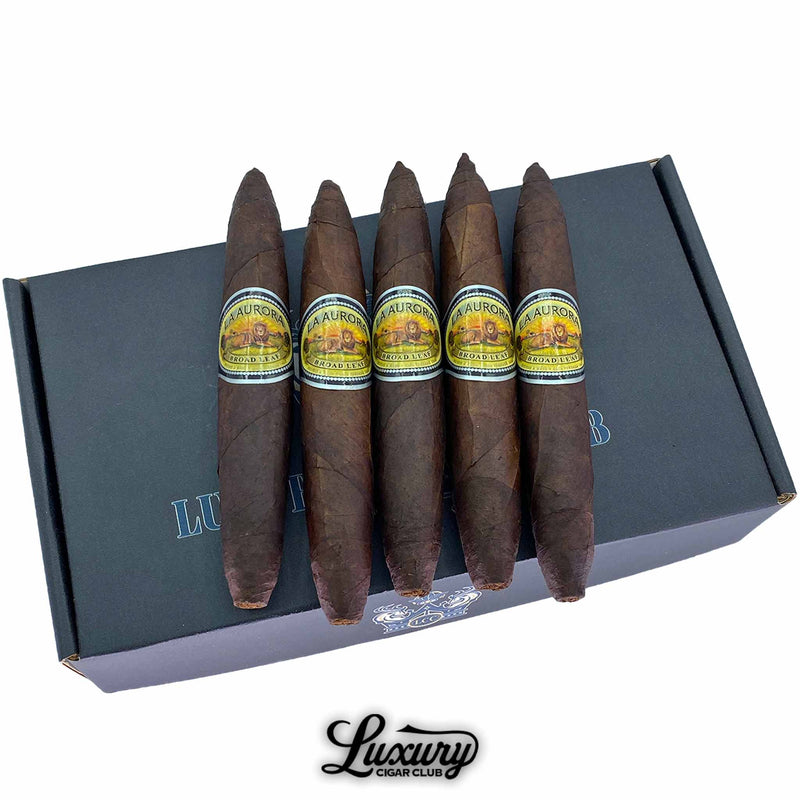 Close up of La Aurora Preferido No. 1 Black Broadleaf Perfecto cigars resting on Luxury Cigar Club packaging, highlighting the rich dark wrapper, tapered perfecto ends, and the classic La Aurora label, luxury Dominican cigars online