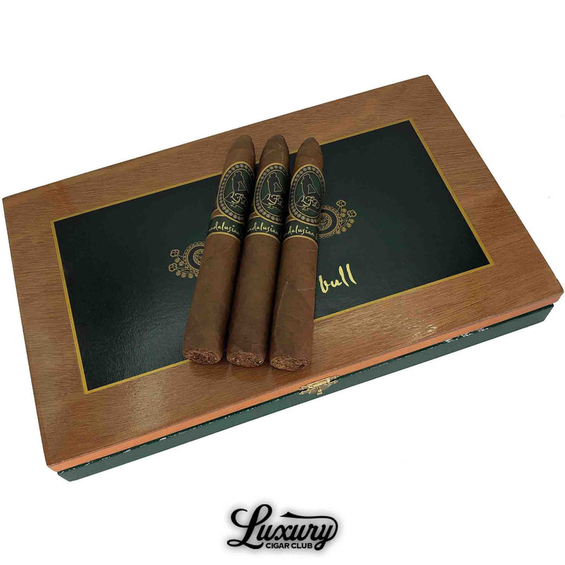 Three La Flor Dominicana Andalusian Bull Unicorn cigars displayed on a decorative cedar box with green and gold detailing, handcrafted premium release from Luxury Cigar Club