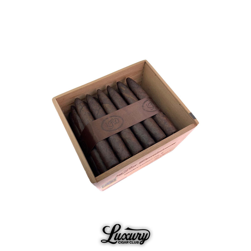 Open wooden box of La Flor Dominicana Cabinet No. 6 Maduro Limited Release cigars, featuring dark, oily torpedo-shaped cigars bound with a brown LFD band across the center. Luxury Cigar Club logo below.
