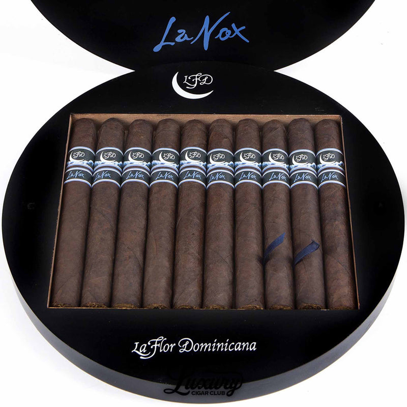 Close-up of La Flor Dominicana La Nox Toro cigars inside the circular box, showcasing the dark, oily wrappers and sleek blue and silver bands that reflect the elegant nighttime motif, featured by Luxury Cigar Club.