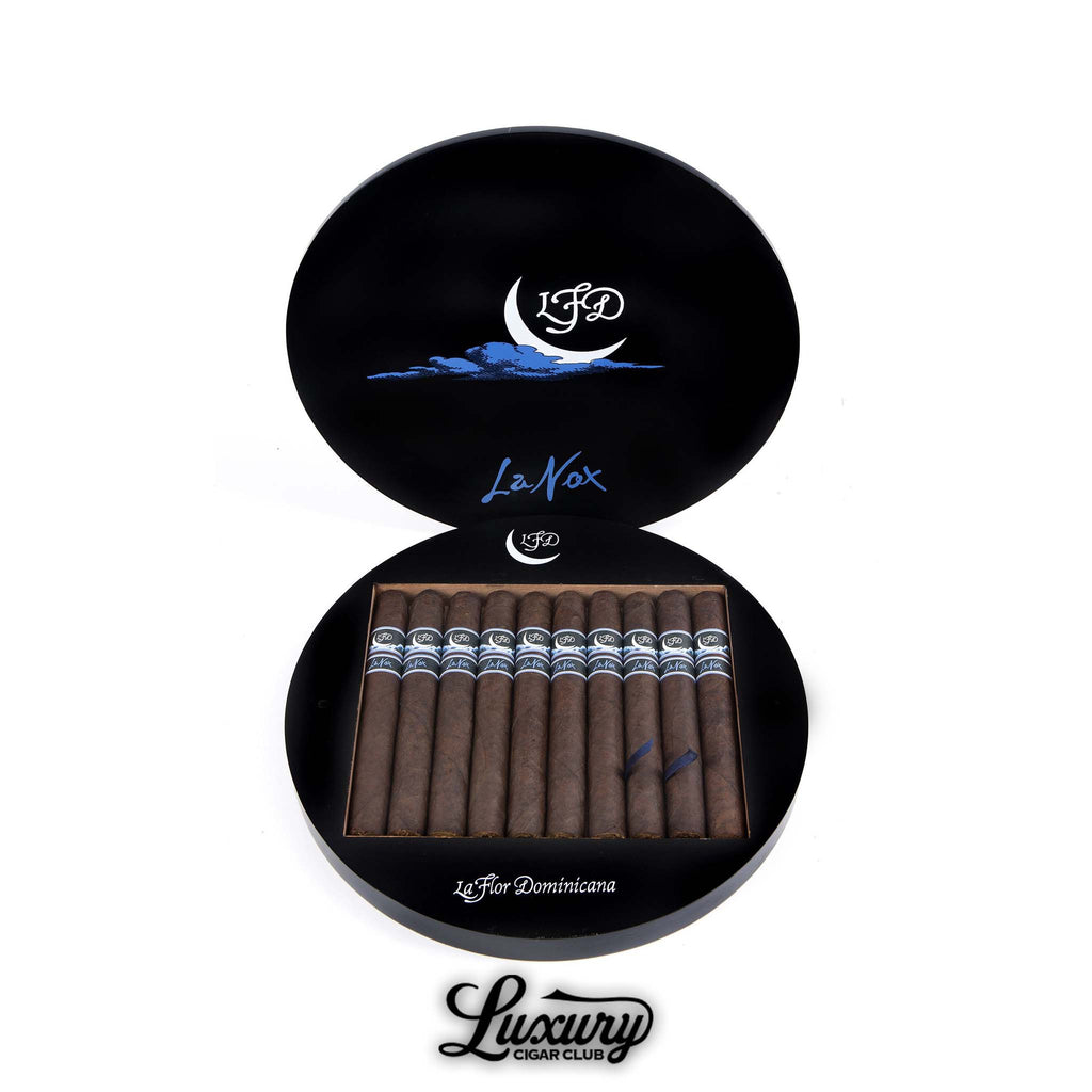 La Flor Dominicana La Nox Toro cigars displayed in their distinctive round black box featuring a crescent moon and blue accents, symbolizing the night theme, presented by Luxury Cigar Club.