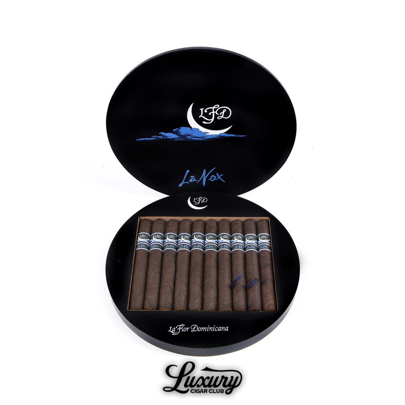 La Flor Dominicana La Nox Toro cigars displayed in their distinctive round black box featuring a crescent moon and blue accents, symbolizing the night theme, presented by Luxury Cigar Club.