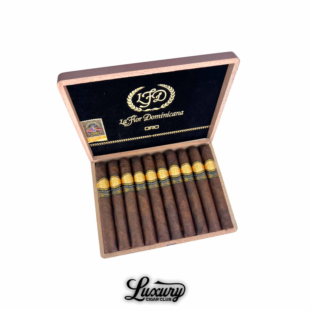 Luxury Cigar Club La Flor Dominicana Oro Maduro No 6 open cigar box showing neatly arranged dark maduro cigars with gold and black LFD Oro bands against a black and gold interior lid.