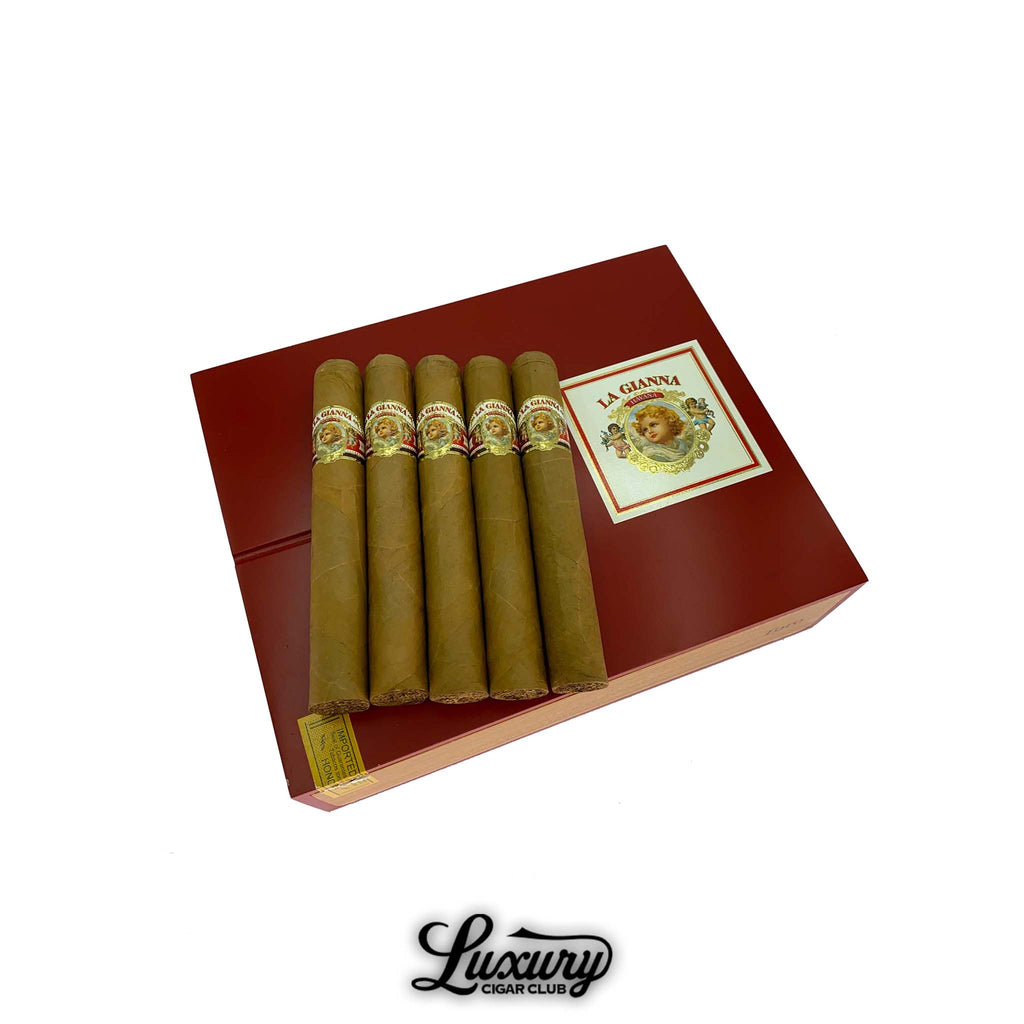 Five La Gianna Natural Toro cigars displayed on top of a deep red La Gianna cigar box, featuring the brand’s classic label with a cherub portrait surrounded by gold and floral detailing. The cigars have smooth, golden Connecticut wrappers that emphasize their premium craftsmanship and mild flavor profile. The Luxury Cigar Club logo appears below the box on a white background. Luxury Cigar Club.