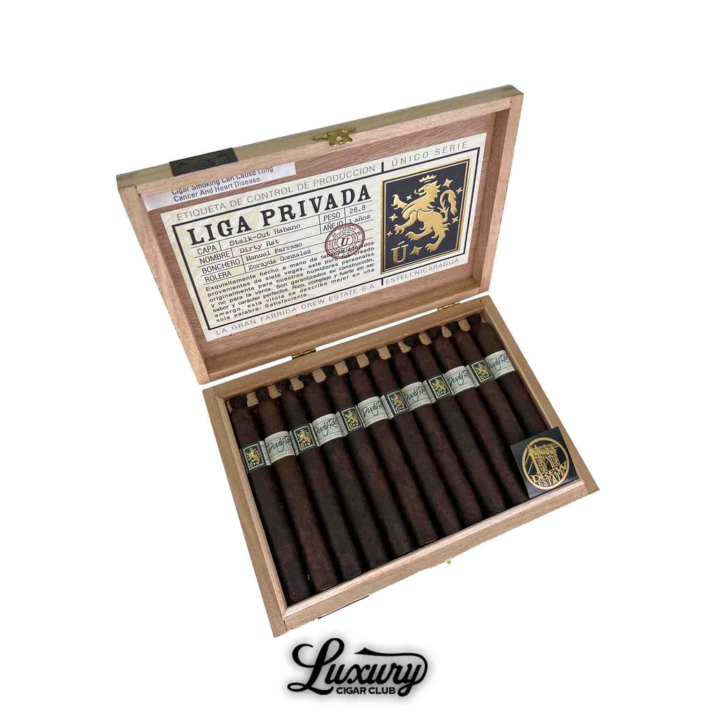 Open box of Liga Privada Único Serie Dirty Rat cigars, showcasing twelve dark brown cigars with pigtail caps and gold-accented silver bands, neatly arranged in a wooden box with a detailed Liga Privada production label on the inside lid; Luxury Cigar Club logo beneath.