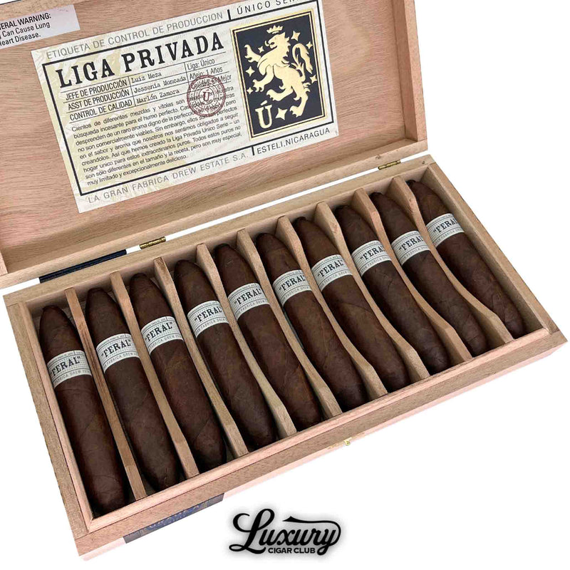 Detailed view of Liga Privada Unico Series Feral Flying Pig cigars inside their wooden box, highlighting the oily Maduro wrapper, unique pig-tail caps, and bold silver “Feral” bands, presented by Luxury Cigar Club.