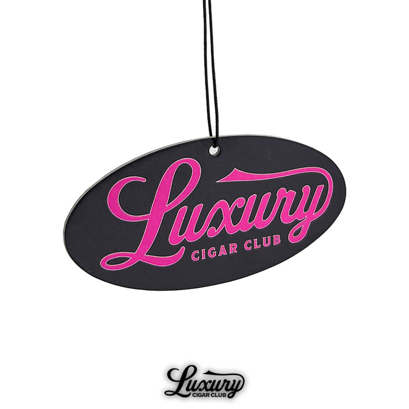 Close-up image of the Luxury Cigar Club sandalwood air freshener, highlighting the oval black design with pink logo text for a stylish and bold accessory.