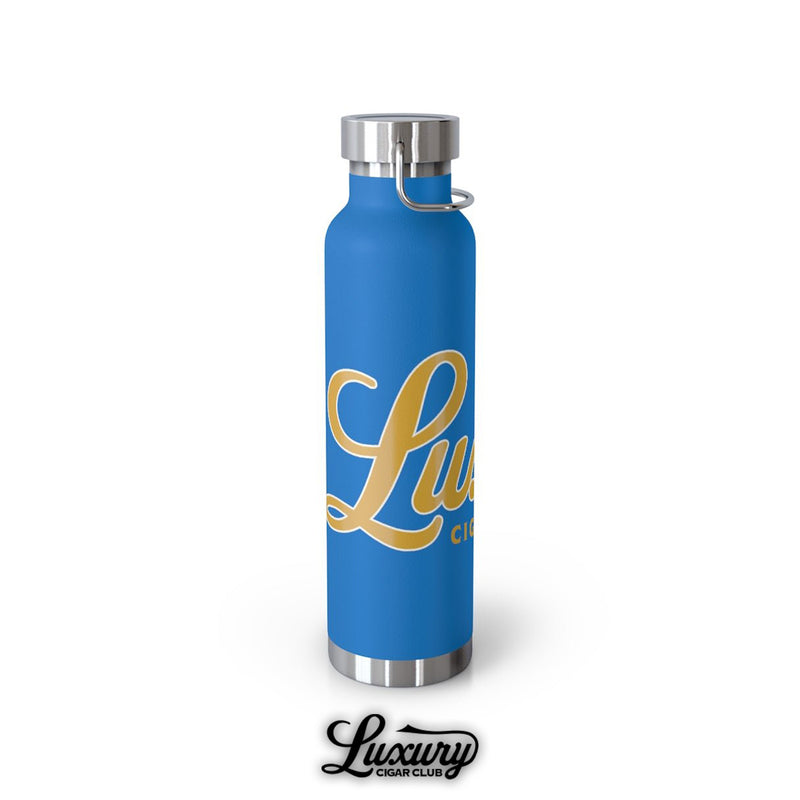 Side angle of Luxury Cigar Club pebble blue 22oz insulated bottle with metallic silver handle cap and large gold cursive logo