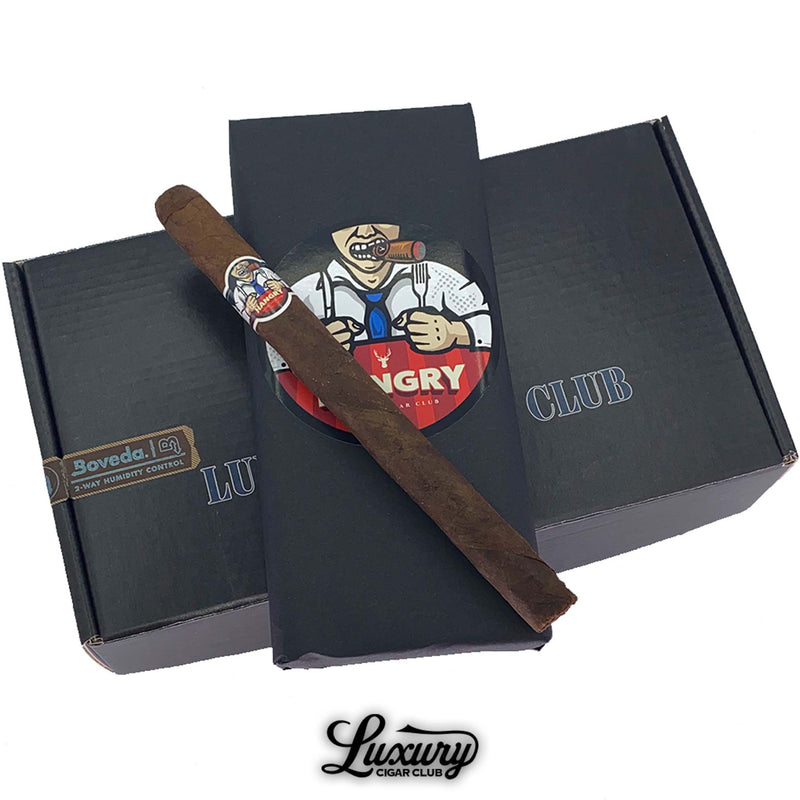 Close-up of Hangry by Martinez Lonsdale cigar resting on Luxury Cigar Club packaging featuring bold cartoon-style artwork