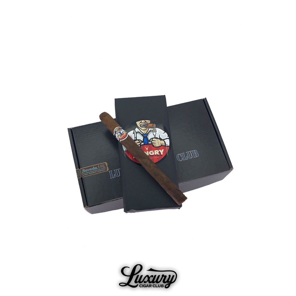 Luxury Cigar Club Hangry by Martinez Lonsdale cigar displayed on top of branded black boxes with cigar-themed artwork in the background