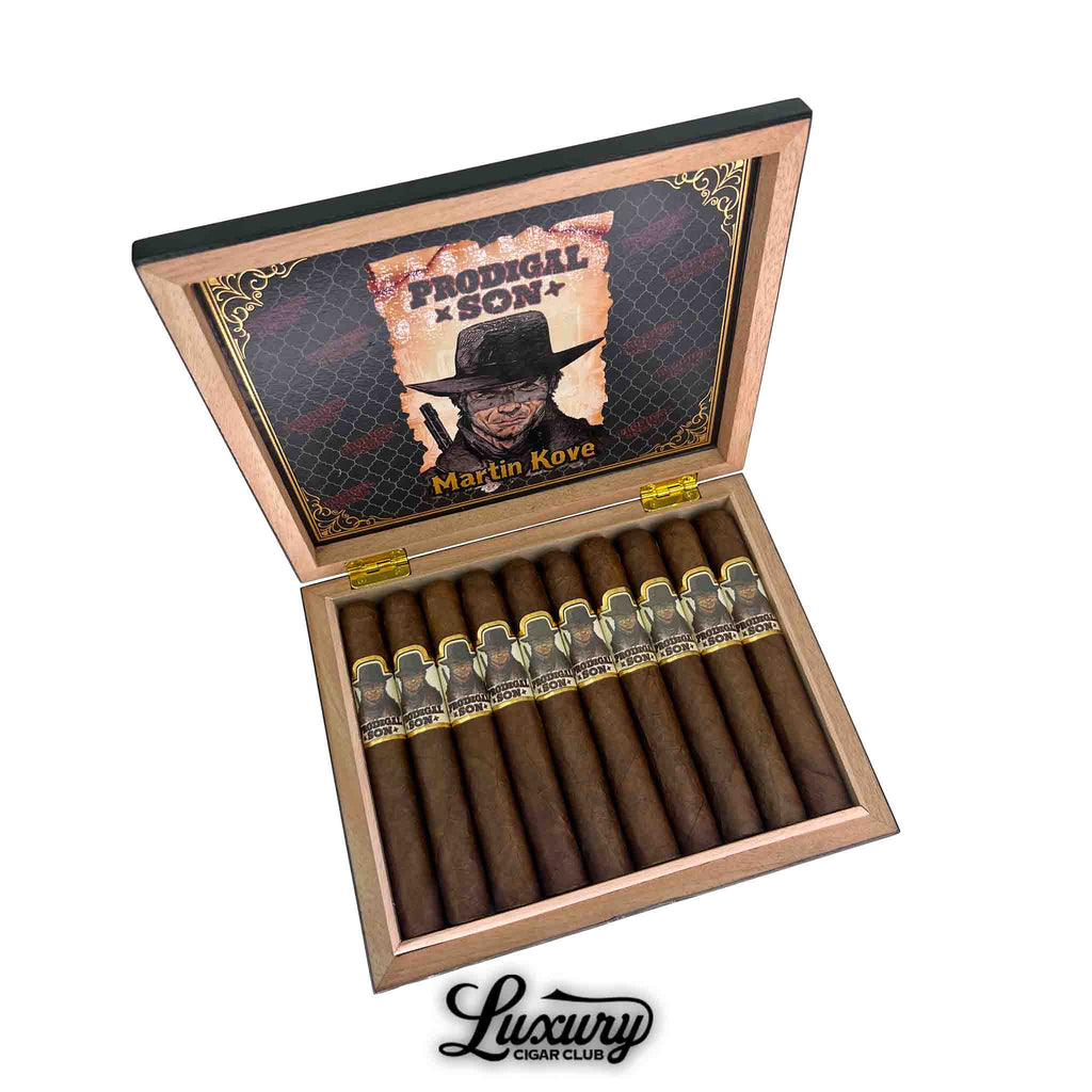 Open cedar box of Martin Kove Prodigal Son Toro cigars with 12 neatly arranged cigars featuring bands illustrated with Martin Kove in a cowboy hat, branding “Prodigal Son” visible inside lid, displayed by Luxury Cigar Club.