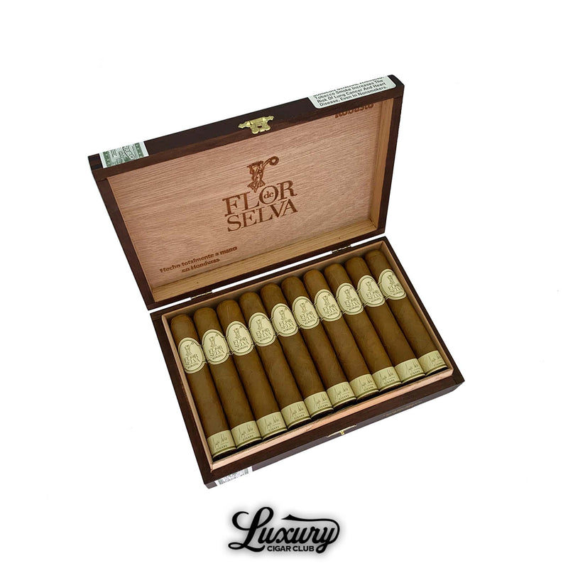Open box of Maya Selva Flor de Selva Classic Robusto cigars with golden brown wrappers and cream-colored bands inside a natural wood box. Luxury Cigar Club logo displayed below.