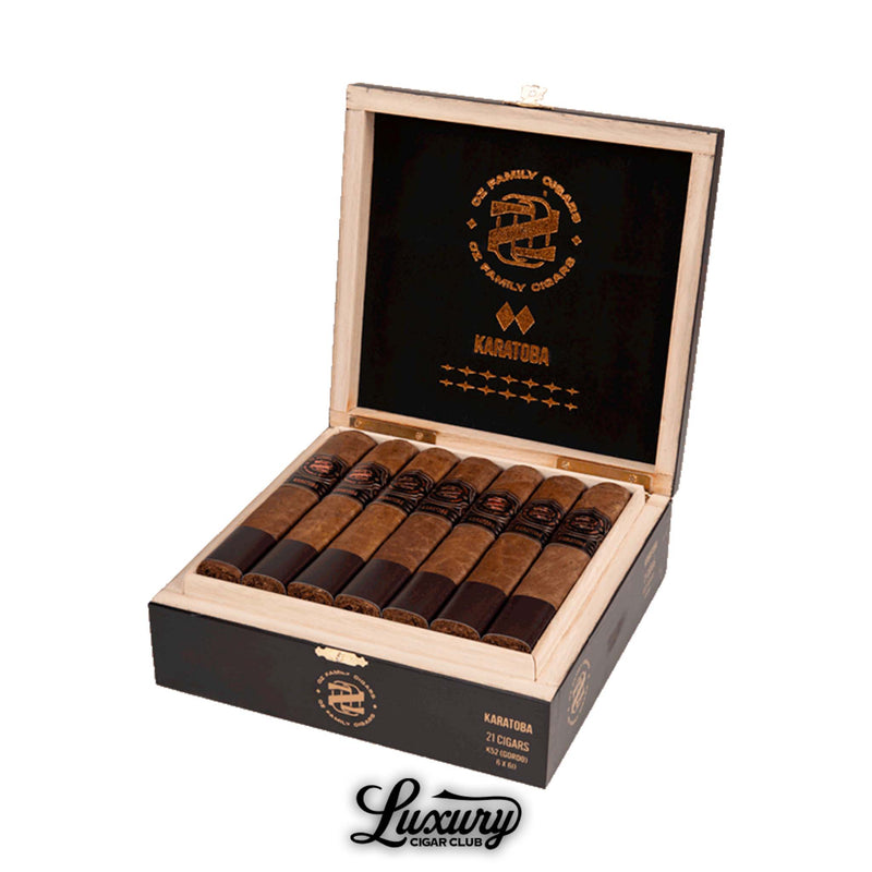 Open box of Ozgener Family Cigars Karatoba Robusto cigars, showing 21 hand-rolled cigars with dark brown wrappers and copper-accented black bands, inside a black-and-wood box marked with the Karatoba logo and branding, displayed above the Luxury Cigar Club logo.