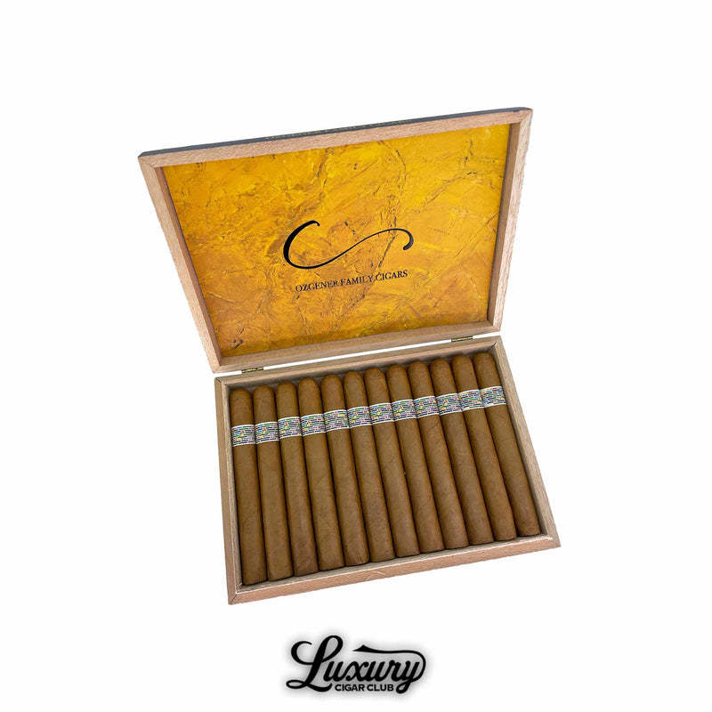 Open wooden box of Ozgener Family Cigars Pi Synesthesia Limited Edition Toro cigars, featuring an elegant yellow interior lid with the Ozgener Family Cigars logo. The cigars are neatly arranged in a row, each wrapped in a golden-brown leaf with colorful, mosaic-patterned bands, symbolizing artistry and precision. Displayed above the Luxury Cigar Club logo. Luxury Cigar Club.