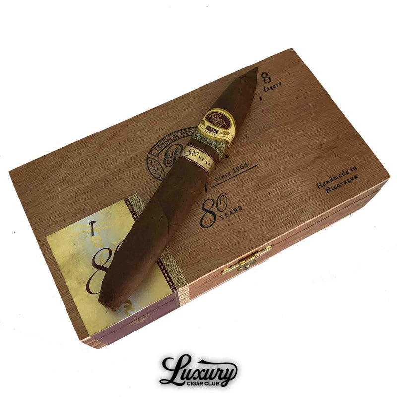 Single Padron 1926 80 Year Natural Perfecto cigar resting on the commemorative 80th anniversary box, featured by Luxury Cigar Club.