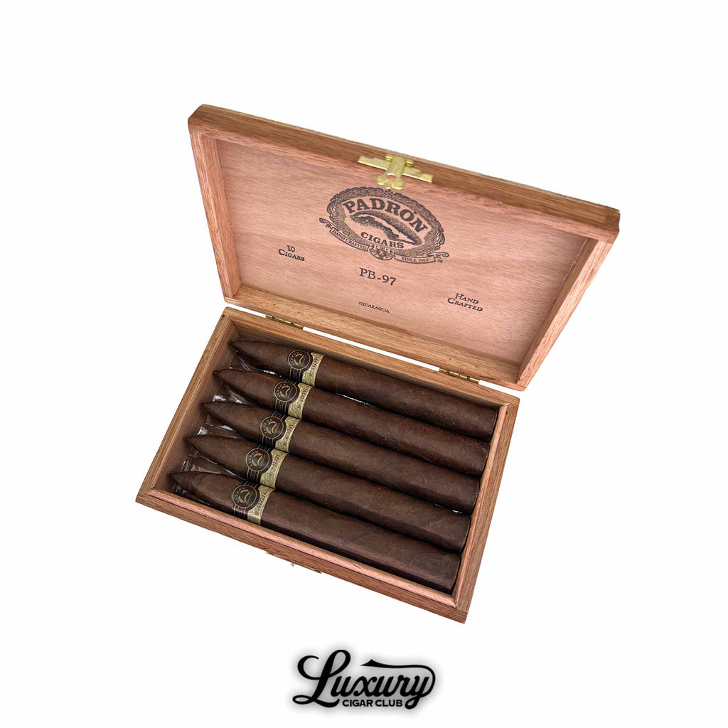 Open wooden box of Padron Black Maduro Unicorn PB97 cigars displayed in rows with gold and black bands, Luxury Cigar Club logo beneath.