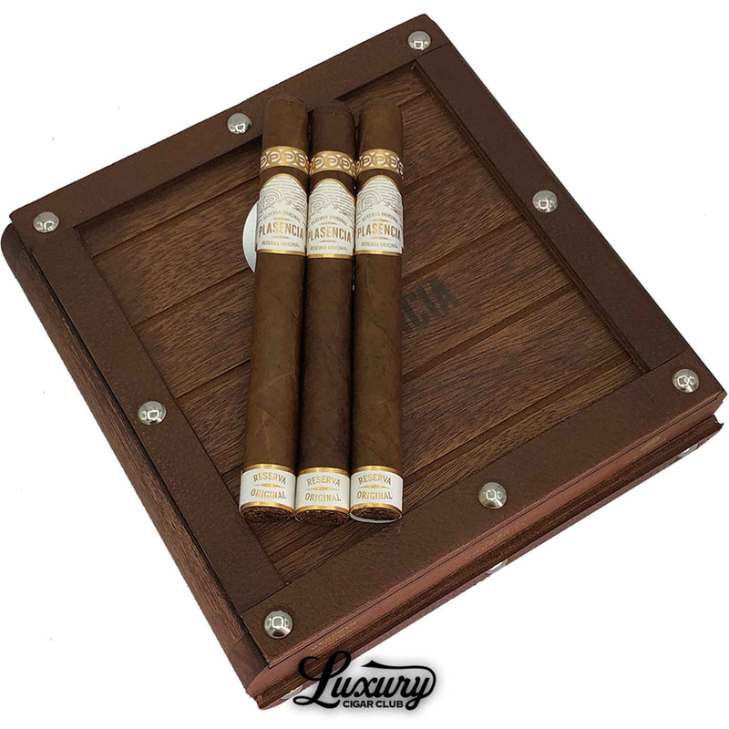 Close-up view of Plasencia Reserva Original Churchill cigars displayed on a decorative wooden box with metal accents, highlighting premium organic Nicaraguan craftsmanship from Luxury Cigar Club.