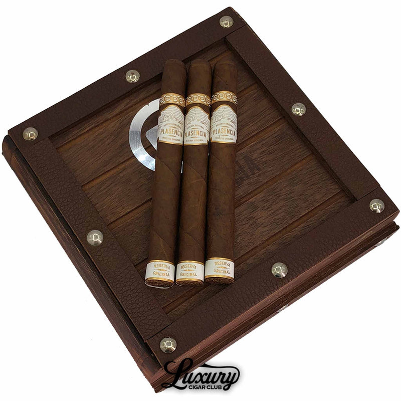 Close-up image of Plasencia Reserva Original Corona cigars resting on a rustic wooden box with metal rivets, highlighting premium Nicaraguan organic tobacco at Luxury Cigar Club.