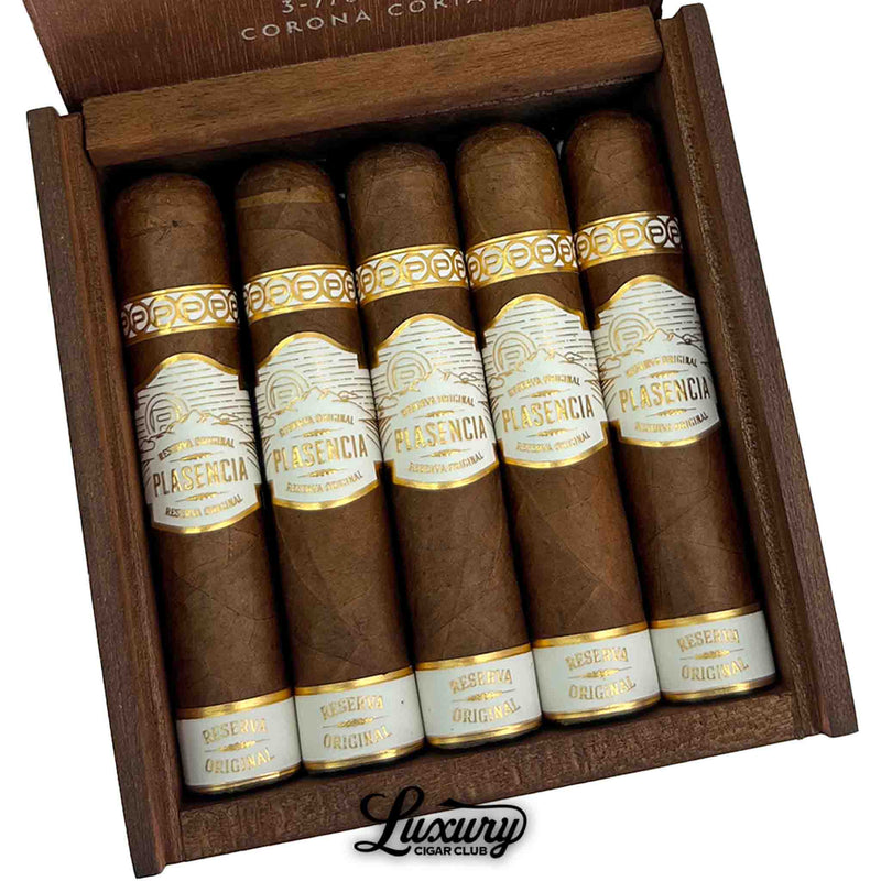 Close-up of Plasencia Reserva Original Corona Corta cigars showing smooth, natural wrappers and refined gold-embossed bands inside a cedar-lined box from Luxury Cigar Club.