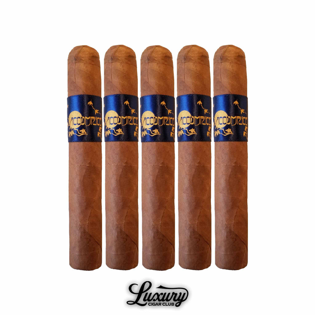 Set of five Principle Accomplice Connecticut cigars standing upright, each wrapped in a smooth golden-brown Ecuadorian Connecticut wrapper. The cigars feature deep blue and gold bands with the Accomplice logo and lizard design, symbolizing refined craftsmanship and elegance. Displayed on a white background above the Luxury Cigar Club logo. Luxury Cigar Club.