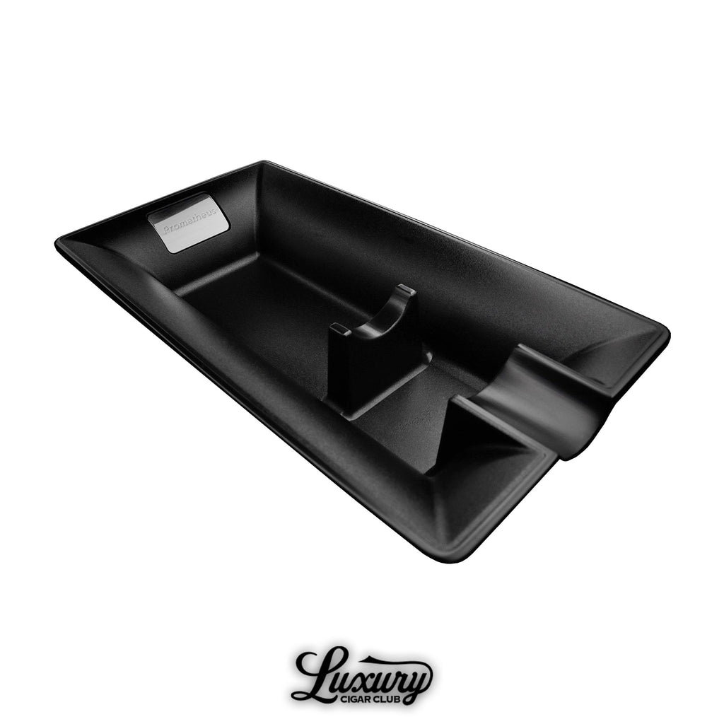 Prometheus Single Cigar Black Matte Metal Ashtray with a minimalist rectangular design, deep basin, and built-in cigar rest. Features a metal Prometheus logo plate and is displayed above the Luxury Cigar Club logo.