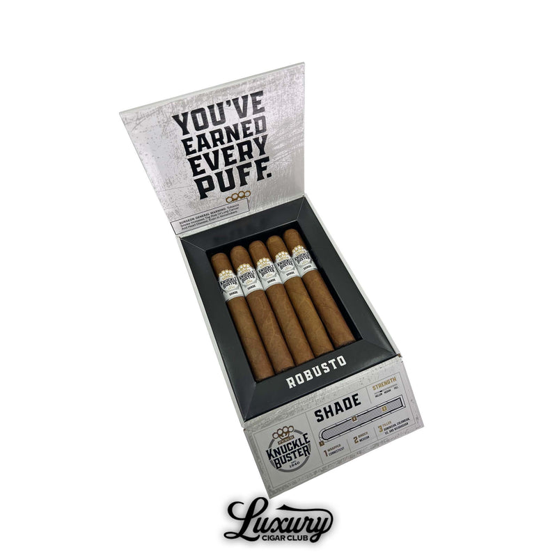Open box of Punch Knuckle Buster Connecticut Robusto cigars showing tan wrappers with white and gold bands labeled “Knuckle Buster Shade.” Inside lid reads “You’ve Earned Every Puff.” Luxury Cigar Club logo displayed below.
